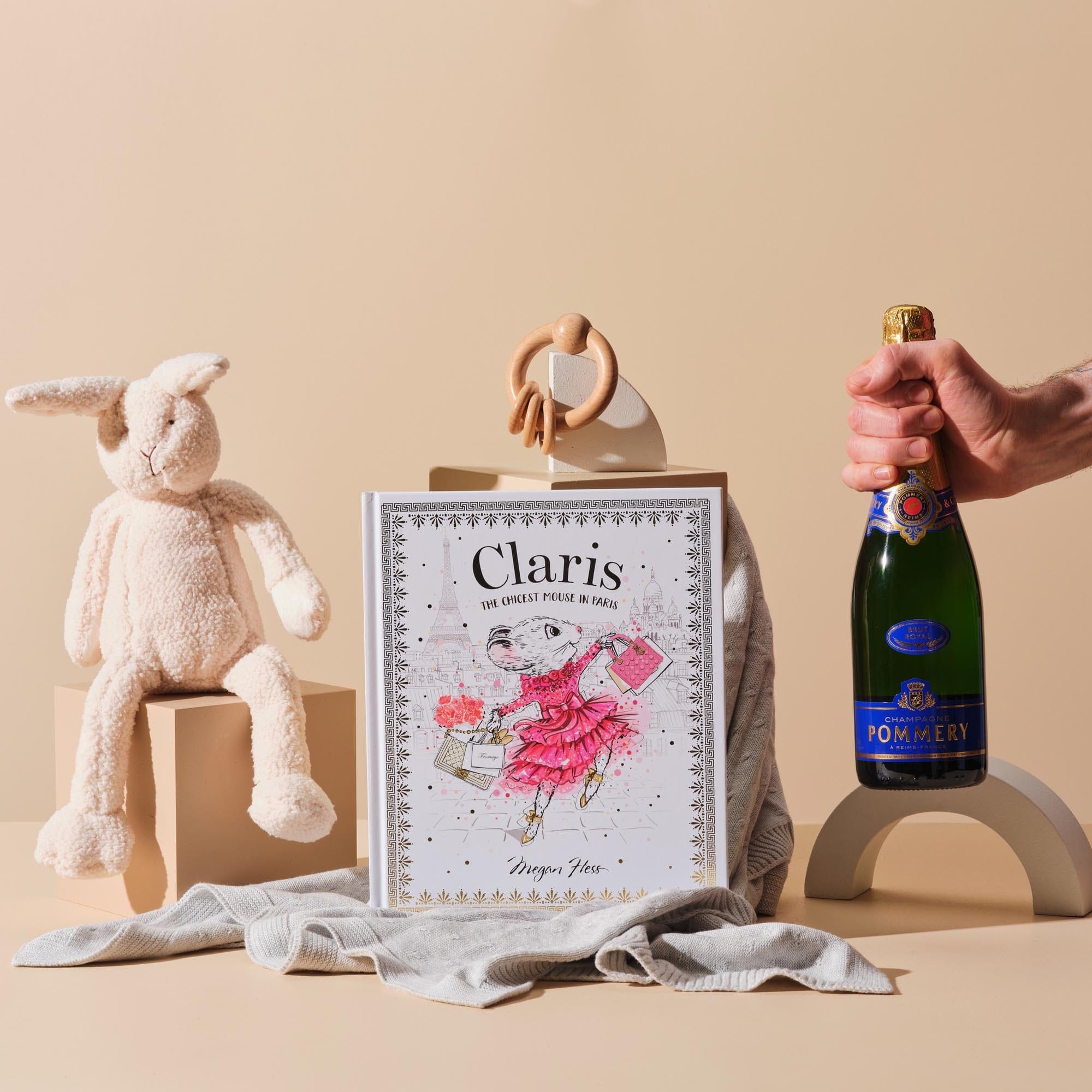 This image is dressed with the Purebaby's Essential Blanket, Bonnie the Bunny toy, Purebaby's Teething Ring and is featuring Claris, the Chicest Mouse in Paris written by Megan Hess. Also included in this image is a gift for Mum; the Champagne Pommery Brut Royal.