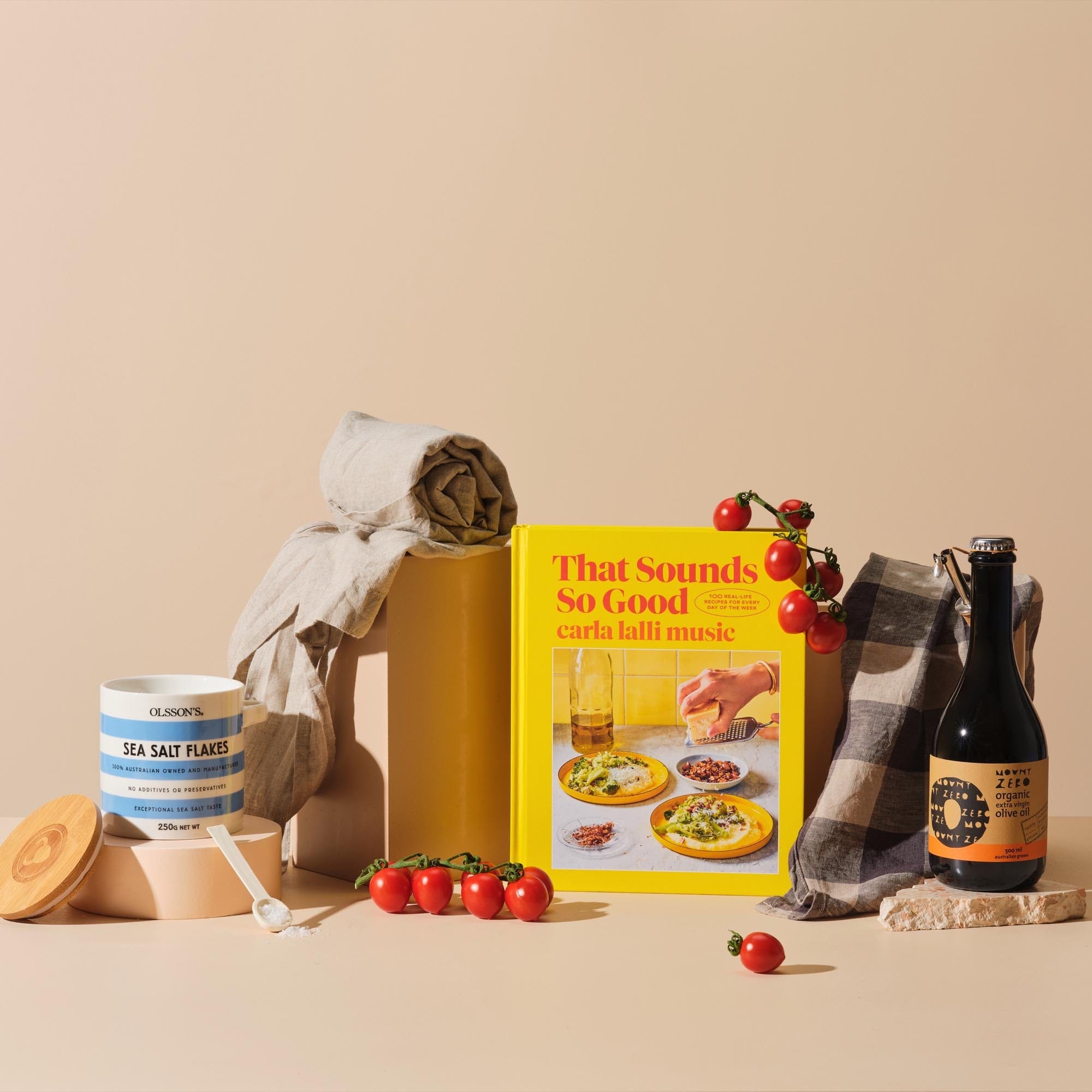 This is the Larder Love gift bundle from Handsel. Included in this image is That Sounds So Good, Olive oil, Sea salt flakes and an Apron/Tea towel